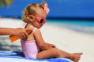applying sunscreen to little girl baby